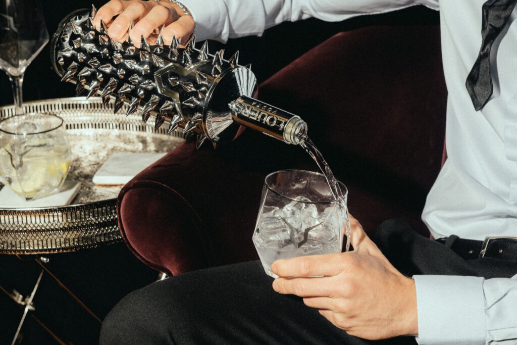 Elegancko ubrany mężczyzna nalewa wódkę LOUERS do szklanki z lodem