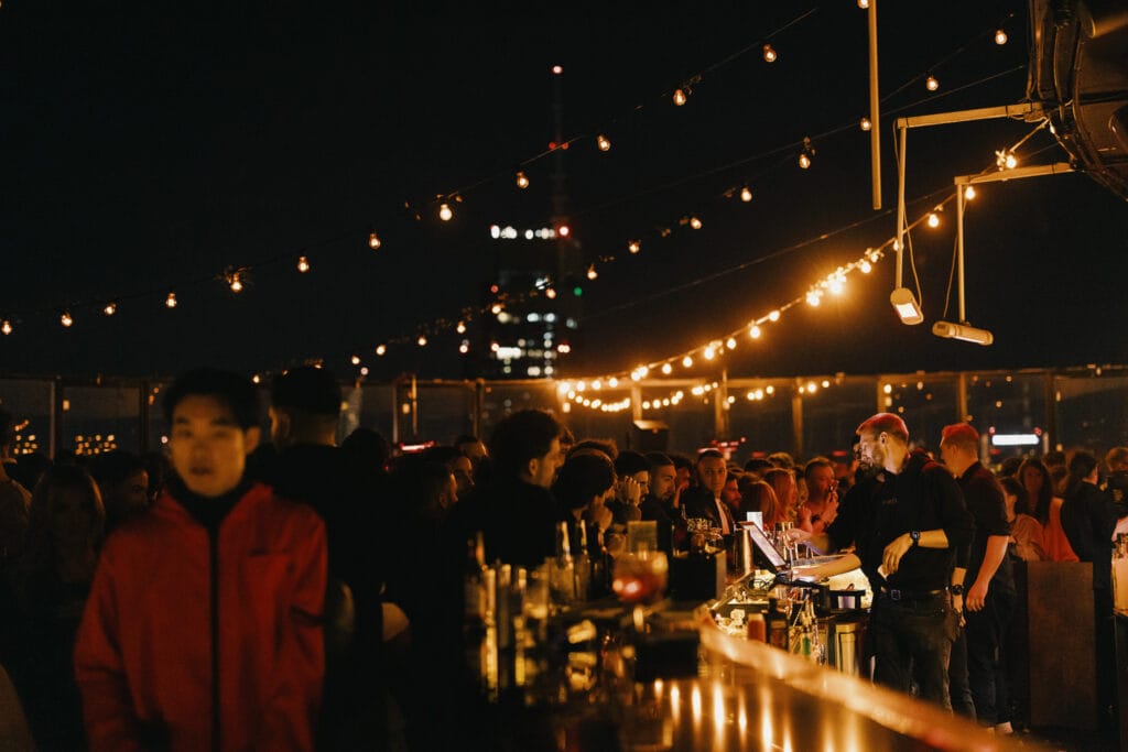 Illuminated rooftop bar in Warsaw center with a bartender and a view of the city at night